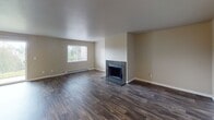 This single-floor residence in Tacoma, WA offers a well-designed layout with a variety of thoughtful finishes throughout. The living room serves as a central gathering space, featuring rich dark hardwood-style flooring, a tile-surround wood-burning fireplace, and a window that brings in natural light. A ceiling fan and sliding glass doors in the adjoining area provide both comfort and convenient outdoor access.

The kitchen is equipped with dark espresso cabinetry, stainless steel appliances including a refrigerator and range, and a raised breakfast bar that opens to the living area — creating an efficient and connected space for cooking and entertaining.

The bedrooms are finished with plush carpeting and offer ample natural light through well-placed windows. One bedroom includes built-in shelving and direct access to a bathroom vanity area, enhancing its functionality.

The bathrooms feature dark-framed mirrors, dark cabinetry with light countertops, and wood-look tile flooring, lending a clean, modern aesthetic. A separate half-bath with a framed mirror and white countertop provides added convenience.

Throughout the space, neutral wall tones and consistent finishes create a cohesive and inviting atmosphere suited for comfortable everyday living.