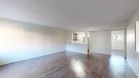 Located at 1801 W Garvey Ave in Alhambra, CA, this single-story one-bedroom, one-bathroom unit offers a functional and well-designed layout. The open-concept living and dining area is bright and spacious, featuring hardwood-style flooring that runs throughout the entire unit, clean white walls, and natural light streaming in through multiple windows. A pass-through counter connects the living area to the kitchen, which is equipped with wood cabinetry, a tile backsplash, and full-size appliances including a refrigerator. The bedroom is comfortably sized, offering a wide window with outdoor views of the surrounding neighborhood, a wall-mounted AC unit, and two closets — one featuring a rich dark wood finish and the other an open shelving design, providing ample storage. Built-in shelving in the living area adds additional organizational versatility. The bathroom is clean and efficiently designed, featuring a full tub-shower combination with brushed nickel fixtures, white cabinetry, and wood-style flooring that complements the rest of the unit. The overall aesthetic is clean, bright, and move-in ready, making this a practical and comfortable home in a convenient Alhambra location.