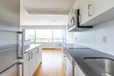 Located at 265 Russell Hill Rd in Toronto's desirable Forest Hill neighbourhood, this well-appointed one-bedroom, one-bathroom unit offers a clean, modern aesthetic across a single floor. Warm honey-toned hardwood flooring runs throughout, unifying the space and lending a bright, welcoming atmosphere.

The open living area is a standout feature, anchored by expansive floor-to-ceiling windows that flood the room with natural light and frame views of the surrounding Toronto cityscape. Baseboard heating lines the perimeter beneath the windows, ensuring year-round comfort. The crisp white walls complement the clean, minimal design throughout.

The galley-style kitchen is thoughtfully laid out with white cabinetry on both sides, dark countertops, stainless steel appliances including a built-in microwave, and a deep sink — making efficient use of the available space. Recessed and flush-mount lighting provide practical illumination.

The bedroom is a comfortable, private retreat with its own window overlooking city views, hardwood flooring, and white walls that create a calm, restful environment. A partial glass partition near the kitchen area adds a contemporary design touch.

The bathroom is finished with large-format neutral tile surrounding a soaking tub and shower combination, accented by chrome fixtures and a small window for natural light.