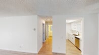 Located at 2636 Grand Ave in the vibrant Pacific Beach neighborhood of San Diego, CA, this single-floor unit offers a clean, modern aesthetic throughout. Light-toned hardwood-style flooring runs continuously across the living areas, complemented by crisp white walls and textured ceilings that lend a classic character to the space.

The open living area is a standout, featuring a sliding glass door dressed with vertical blinds that flood the room with natural light and provide access to an outdoor area. The layout flows seamlessly into a well-designed hallway connecting the private spaces.

The galley-style kitchen is thoughtfully appointed with white shaker cabinetry, quartz countertops, open shelving, and a full suite of stainless steel appliances including a refrigerator, range, built-in microwave, and dishwasher. A undermount sink with brushed nickel fixtures adds a refined touch. Bright overhead lighting enhances the kitchen's clean, functional design.

The bedroom is generously proportioned with a large window that welcomes natural light and offers views of the surrounding neighborhood greenery. The bathroom features a white vanity with quartz countertop, an undermount sink, brushed nickel hardware, a full tub-shower combination, and a large mirror — all finished in a cohesive, neutral palette that conveys a sense of freshness and simplicity throughout the unit.