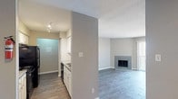 This single-floor, 2-bedroom, 1-bathroom residence offers a thoughtfully laid-out living space finished with wood-style flooring that runs consistently throughout. The open living area is a standout feature, highlighted by a tiled fireplace that serves as a natural focal point. A pass-through window connects the living space to the kitchen, enhancing the sense of openness. Sliding glass doors and additional windows allow natural light to fill the room.

The galley-style kitchen is efficiently designed, featuring white cabinetry, granite-look countertops, a stainless steel sink, and black appliances including a refrigerator, electric range, and dishwasher. Track lighting and access to a laundry area add to the kitchen's functionality.

Both bedrooms are well-proportioned, each featuring ceiling fans with light fixtures and windows fitted with blinds that bring in natural light. The neutral gray walls throughout create a clean, modern aesthetic.

The bathroom includes a white vanity with ample cabinet storage, a large mirror with Hollywood-style lighting, and a tiled shower-tub combination. The textured ceilings and consistent flooring tie the entire unit together into a cohesive, move-in-ready living space.