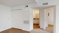 This 1-bedroom, 1-bathroom single-story unit offers a thoughtfully arranged layout that maximizes every square foot. The living room immediately impresses with soaring vaulted ceilings, a ceiling fan, and a striking arched window flanked by additional windows fitted with blinds, filling the space with natural light and views of surrounding greenery. Soft carpeting throughout the living and bedroom areas adds warmth and comfort.

The kitchen features white cabinetry, dark countertops, and wood-look vinyl flooring. It is equipped with a full suite of white appliances, including a refrigerator, dishwasher, electric range with overhead ventilation, and ample cabinet storage. A window above the sink allows for natural light in the cooking area.

The bedroom is a comfortable retreat, carpeted and brightened by its own arched window with blinds. A ceiling fan adds climate control, and a roomy closet with double doors and built-in shelving provides generous storage. The bedroom also offers convenient direct access to the bathroom.

The bathroom is well-appointed with white cabinetry, a large vanity mirror with lighted fixtures, dark countertops, and a full tub-shower combo finished with classic white tile. Wood-look flooring ties the space together cleanly. Throughout, the unit maintains a bright, neutral palette that lends a clean and open ambiance.