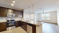 Located at 5290 Big Island Dr in Jacksonville, FL, this thoughtfully designed 2-bedroom, 2-bathroom residence offers a comfortable and modern living experience across a single floor. The open-concept kitchen and living area serves as the heart of the home, anchored by a large granite-topped island with a double stainless steel sink and elegant pendant lighting. Dark espresso cabinetry contrasts beautifully with the light granite surfaces, while stainless steel appliances—including a refrigerator, range, microwave, and dishwasher—complete the chef-friendly kitchen. A white subway tile backsplash adds a clean, contemporary touch. The living area flows naturally from the kitchen, featuring warm hardwood-style flooring, a ceiling fan, and multiple windows dressed with blinds that invite ample natural light. A dedicated dining nook with track lighting and a glazed entry door adds versatility to the space. Both bedrooms are carpeted and well-lit with large windows. The generously sized primary bedroom includes a walk-in closet with wire shelving. The bathrooms are finished with granite vanity tops, dark cabinetry, and large-format tile flooring, with a shower-tub combination in at least one bath. Two dedicated closets provide excellent storage throughout.