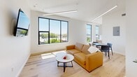 Located at 440 Monroe Ave in Memphis, TN, this modern one-bedroom, one-bathroom unit offers a thoughtfully designed layout that maximizes every inch of its compact footprint. The open-plan living area is a bright, airy space anchored by large black-framed windows that flood the room with natural light and offer pleasant views of the surrounding urban greenery. Light hardwood floors run throughout, complementing the crisp white walls and contemporary linear lighting fixtures suspended from the ceiling.

The living area flows seamlessly toward a dining space and kitchen, maintaining a cohesive, minimalist aesthetic. The bedroom is generously proportioned, featuring dramatic floor-to-ceiling black-framed windows on two walls that bathe the room in sunlight and provide sweeping city and treetop views. Exposed ductwork along the ceiling adds an industrial design touch that contrasts stylishly with the clean white surfaces.

The bathroom is efficiently laid out, featuring a tiled shower-tub combination, toilet, and a convenient stacked in-unit washer and dryer. The warm hardwood flooring continues here, maintaining design continuity throughout the unit. A dedicated closet provides practical storage. This unit combines modern urban aesthetics with functional living, making it an ideal space in the heart of Memphis.