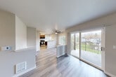 Located in Bothell, WA, this three-bedroom, one-bathroom residence offers a well-organized single-floor layout designed for comfortable everyday living. The open-concept living and dining area is anchored by wood-style laminate flooring, a ceiling fan, and large sliding glass doors that lead to a private balcony overlooking a landscaped outdoor setting — filling the space with natural light and views of the surrounding greenery.

The kitchen is thoughtfully appointed with rich dark-wood cabinetry, white quartz countertops, a stainless steel range with over-the-range microwave, a stainless steel sink, and a window that brings in additional natural light. A peninsula counter separates the kitchen from the living area, creating a functional open flow.

The three bedrooms feature plush carpeting, baseboard heating, and windows with neighborhood and outdoor views. The primary bedroom includes access to two closets, one of which is a walk-in with built-in shelving and hanging rods. A connecting hallway links the bedrooms seamlessly.

The full bathroom is finished with wood-look flooring, a dark-wood vanity with a white countertop, a large mirror, and a shower-tub combination. Throughout the residence, neutral tones and clean lines create a calm, move-in-ready atmosphere.