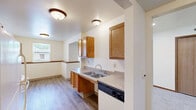 Located at 650 York Creek Dr NW in Comstock Park, Michigan, this single-floor residence offers three bedrooms, two bathrooms, a kitchen, and dedicated hallway and closet spaces — all thoughtfully arranged in a compact, efficient layout. The kitchen serves as a central hub, featuring warm honey-toned oak cabinetry, a double stainless steel sink, laminate countertops, and white appliances including a range and refrigerator. Durable wood-look vinyl plank flooring runs throughout the kitchen and living areas, while soft carpeting provides comfort in the bedrooms. A dining area adjacent to the kitchen benefits from a window that brings in natural light. The spacious primary bedroom includes a wall-mounted A/C unit, baseboard heating, and a closet with built-in shelving. The additional bedrooms are bright and functional, each featuring windows with exterior views and baseboard heating. Both bathrooms are finished in neutral tones with wood-look flooring; one includes a full bathtub with grab bars and a wall-mounted sink, while the second features a vanity with oak cabinetry. Warm wood trim accents are consistent throughout, lending a cohesive and tidy character to the entire residence.