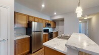 Located at 941 Taylor Station Rd in Gahanna, Ohio, this single-floor unit offers a well-designed layout with a cohesive blend of modern finishes and functional living spaces. The kitchen is a standout feature, showcasing warm honey-toned cabinetry, striking marble-style countertops, and a full suite of stainless steel appliances including a refrigerator, range, and over-the-range microwave. A peninsula with a built-in sink and seating overhang serves as both a prep area and casual dining space, illuminated by a pendant light fixture above. Hardwood-style flooring runs throughout the kitchen and main living areas, adding warmth and durability. The bedrooms are carpeted for comfort and feature neutral gray walls, natural light from windows with blinds, and closet storage. One bedroom includes a walk-in closet. The bathroom is finished with a wood-toned vanity, marble-style countertop, a large mirror, a walk-in shower, and hardwood-style flooring. Recessed lighting in the kitchen and an open-concept connection between the kitchen and living areas contribute to a bright, airy atmosphere throughout this practical and well-appointed home.