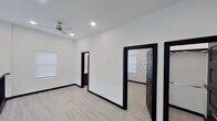 Located at 605 E 16th Street in Weslaco, Texas, this single-floor space showcases a striking modern design characterized by a crisp black-and-white color palette. The interior is unified by light wood-look flooring that runs throughout, providing a warm contrast to the bright white walls and bold black door frames, baseboards, and trim that define each room.

The layout, visible through a 3D scan, reveals a well-organized floor plan with multiple rooms connected by wide doorways framed in deep black molding. Recessed lighting illuminates the interiors throughout, complemented by ceiling fans with contemporary brushed nickel finishes in the living and bedroom areas. Windows dressed with white blinds allow natural light to filter in, maintaining the airy, open atmosphere.

A standout upper-level hallway features a sleek black metal railing overlooking a double-height open area below, adding architectural depth to the space. The bathroom is thoughtfully finished with white subway tile surrounding the tub and shower, a dark-cabinetry vanity with a white quartz countertop, and recessed lighting for a clean, polished look.

Overall, the space presents a cohesive, contemporary aesthetic with high-contrast design details and quality finishes throughout.