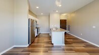 This one-bedroom, one-bathroom unit at 320 W 3rd St N in Newton, Iowa offers a well-designed, efficient layout across a single floor. The open-concept kitchen and living area is anchored by rich hardwood-style flooring that runs throughout the main space. The kitchen is thoughtfully equipped with stainless steel appliances — including a refrigerator, electric range, microwave, and dishwasher — complemented by white cabinetry, granite-style countertops, and a peninsula with a built-in sink, ideal for casual dining or meal prep. Recessed lighting illuminates the space, enhancing its clean, modern aesthetic. The bedroom offers plush carpeting and a window with outdoor views, providing a quiet and comfortable retreat. Adjoining the bedroom is a full bathroom featuring hardwood-style flooring, a white vanity with ample counter space, a mirror, and a walk-in shower. A dedicated walk-in closet with wire shelving rounds out the private quarters, offering generous storage. Neutral wall tones and consistent finishes throughout the unit contribute to a cohesive, move-in-ready atmosphere suited for practical, comfortable living in Newton, IA.