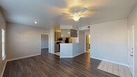 This single-story residence in Katy, Texas offers a practical and well-appointed layout across two bedrooms and two bathrooms. The open living area is finished with dark hardwood-style flooring and neutral gray walls, creating a clean, cohesive aesthetic. A ceiling fan with integrated lighting provides both comfort and illumination, while a large window invites natural light into the space.

The galley-style kitchen is a functional highlight, featuring granite-look countertops, gray cabinetry, a full suite of stainless steel appliances—including a range, microwave, dishwasher, and refrigerator—and light tile flooring. A peninsula connects the kitchen to the living area, enhancing the open flow of the floor plan.

Both bedrooms continue the dark hardwood-style flooring and are equipped with ceiling fans and windows that provide natural light. The bathrooms are finished with light tile flooring; one includes a tub-shower combination with white tile surround and a stone-look vanity countertop, while the other features a vanity with mirror and ample built-in storage. The overall ambiance is clean, neutral, and move-in ready.