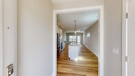 Located at 4422 Nicklaus Dr in Champaign, Illinois, this thoughtfully designed single-story home offers three bedrooms and two bathrooms across a well-appointed floor plan. The open-concept kitchen and living area serves as the heart of the home, featuring white shaker cabinetry, a quartz waterfall island with a double undermount sink, stainless steel appliances, and stylish pendant lighting. Light hardwood flooring flows consistently throughout the main living spaces, enhancing the bright and cohesive aesthetic. The living room stands out with a tray ceiling, a sleek linear fireplace, and a large window that invites natural light. The generously sized primary bedroom includes a walk-in closet outfitted with wire shelving systems for organized storage. The bathrooms are finished in a clean, neutral palette with white vanities and brushed nickel fixtures; the full bath includes a tub-shower combination. A dedicated laundry room doubles as a mudroom, complete with a built-in bench, coat hooks, and upper cabinetry. The attached garage features a concrete floor and an electrical panel. The exterior showcases blue lap siding with board-and-batten accents, stone column detailing, and a covered entry, giving the home a clean, modern curb appeal.