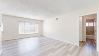 Located at 3910 Coco Ave, Unit 15 in Los Angeles, CA, this 2-bedroom, 2-bathroom unit offers a clean, modern aesthetic across a well-organized single-floor layout. Light wood-style vinyl flooring runs throughout the entire space, creating a cohesive and contemporary look. The living room is bright and open, featuring a textured ceiling, a large window fitted with horizontal blinds that allow ample natural light, and a neutral color palette that enhances the sense of space. The galley-style kitchen is efficiently designed with white shaker cabinetry, dark countertops, stainless steel appliances including a full-size refrigerator, and a double sink — offering a functional cooking environment. Both bedrooms feature the same light flooring, neutral walls, and windows with blinds that bring in natural light. The primary bedroom includes a built-in sliding-door closet with upper cabinet storage, maximizing organization. The two bathrooms are well-appointed, each with white shaker vanities, dark countertops, and wood-style flooring. One bathroom features a tiled tub-shower surround with a window, while the second offers a standalone vanity with a mirror. Clean finishes and consistent design details give the entire unit a refreshed, move-in-ready feel.