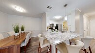 Located at 100 Leslie Oaks Dr in Lithonia, GA, this single-story, 2-bedroom, 2-bathroom residence offers a thoughtfully designed layout across a comfortable footprint. The living room serves as the heart of the home, featuring crown molding, a ceiling fan, wood-look flooring, and a large window that draws in natural light and provides views to the outdoors. Adjacent to the living room, the formal dining area continues the elegant feel with crown molding, a chair rail accent, and hardwood-style flooring — ideal for entertaining. The kitchen is outfitted with crisp white shaker cabinets, granite-style countertops, stainless steel appliances, and light wood-look flooring, offering both style and functionality. The primary bedroom is generously sized with plush carpeting, a ceiling fan, and dual closets, with direct access to an en-suite bathroom featuring white cabinetry, granite countertops, and wood-look tile flooring. The second bedroom is equally comfortable with carpet and a ceiling fan. A dedicated laundry room with full-size washer and dryer hookups and wire shelving adds everyday convenience. Throughout, the home maintains a clean, neutral palette with consistent modern finishes.