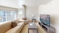 This 2-bedroom, 2-bathroom unit in West Allis, Wisconsin offers a well-designed, single-floor layout that balances comfort and functionality. The open-concept kitchen is outfitted with warm honey-toned cabinetry, stainless steel appliances including a refrigerator, electric range, and dishwasher, and features a central island with a countertop overhang ideal for casual dining. Tile flooring completes the kitchen area, which flows naturally into the adjacent living room.

The living room is bright and welcoming, with plush carpeting, neutral walls, and windows that invite natural light. The space is well-proportioned, offering enough room for a full seating arrangement and entertainment setup.

The primary bedroom is generously sized, featuring soft carpet, large windows with natural light, and direct access to a private en-suite bathroom. The en-suite includes wood-look flooring, a vanity with cabinetry, and a shower with curtain enclosure. The second bedroom is comparably comfortable with ample natural light and carpeted floors. The second bathroom mirrors the clean, simple aesthetic of the first, featuring a tub/shower combination and wood-look flooring. Throughout the unit, consistent wood-tone trim and clean white walls create a cohesive, neutral ambiance.