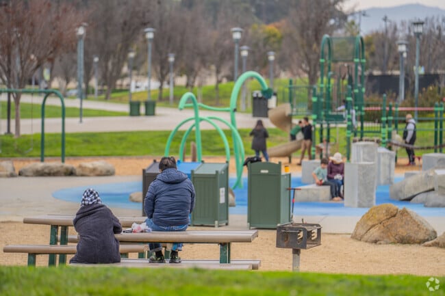 Some parents enjoy the park at Emerald Glen as their children play on.