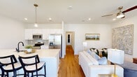 Located at 2009 S Veterans Blvd in Gonzales, Louisiana, this single-story, 4-bedroom, 2-bathroom home offers a well-designed open-concept layout that maximizes functionality and flow. Warm hardwood flooring runs throughout the home, creating a cohesive and inviting atmosphere.

The kitchen is a standout feature, boasting white cabinetry, light quartz countertops, stainless steel appliances including a French door refrigerator and range, a tile backsplash, and a large island with bar seating for four. Pendant lighting above the island adds a modern touch. The kitchen opens seamlessly into the dining and living areas, where high ceilings and recessed lighting enhance the sense of openness.

The living room is bright and airy, featuring a ceiling fan and generous wall space. A dedicated dining area sits adjacent, offering a quiet nook for meals. The four bedrooms are comfortably sized, with the primary bedroom featuring a ceiling fan and a window with natural light. The two bathrooms include one with a tub/shower combo and one with a sleek walk-in shower with black-framed glass doors. A dedicated laundry room houses full-size washer and dryer units with overhead shelving, completing this practical and stylish home.