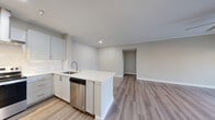 This well-appointed single-floor residence offers a thoughtfully designed layout with modern finishes throughout. The open-concept kitchen is a standout feature, showcasing crisp white cabinetry, bright white countertops, a stainless steel undermount sink, and stainless steel appliances including a dishwasher, refrigerator, and range with a wall-mounted hood. Recessed lighting illuminates the space, which flows seamlessly into the living area. The living room is bright and welcoming, featuring crown molding, a ceiling fan, and sliding glass doors that open to a private outdoor patio, allowing natural light to fill the space. Warm-toned wood-look flooring runs throughout the main living areas, complemented by clean white baseboards and neutral-toned walls. The bedrooms are generously sized, with one featuring mirrored sliding closet doors and another offering access to a walk-in closet and an en-suite bathroom. A dedicated laundry area houses a full-size top-loading washer and dryer. The residence also includes an attached garage with an automatic opener, offering secure parking and additional storage. Light-filled hallways connect each area of the home, creating a cohesive and functional flow throughout.