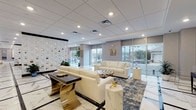 This elegantly designed single-floor amenity space offers a seamlessly connected series of upscale areas, unified by striking marble-effect tile flooring with bold black inlay borders throughout. The expansive lounge area serves as the centerpiece, featuring floor-to-ceiling windows that flood the space with natural light and offer views of the surrounding streetscape. Cream leather sofas, gold-accented furnishings, abstract blue area rugs, and decorative pendant lighting create a refined yet welcoming atmosphere. An ornate geometric screen wall divides zones while adding a sculptural design element.

Adjacent to the lounge, a billiards area provides a social focal point, anchored by a pool table beneath striking gold pendant lights. A built-in bar and kitchen area features a marble-topped island with gold-legged barstools, open shelving, a mounted TV, and mosaic tile backsplash — ideal for entertaining. A dedicated event or meeting room offers flexible open space with patterned carpet, pendant chandeliers, and wall-mounted screens. Additional areas include a darkly appointed media nook with a linear fireplace and built-in display shelving. Together, these spaces deliver a polished, contemporary environment designed for both relaxation and social engagement.