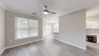 Located at 1150 Baxter Ln in Knightdale, NC, this single-story, 2-bedroom, 2-bathroom home offers a thoughtfully designed layout across a comfortable footprint. The open-concept living, dining, and kitchen area serves as the heart of the home, featuring light wood-look vinyl flooring, neutral warm-gray walls, and large windows fitted with blinds that invite generous natural light. A ceiling fan anchors the living area, while pendant lighting illuminates the dining space. The kitchen is well-equipped with white cabinetry, light countertops, stainless steel appliances including a refrigerator, range, microwave, and dishwasher, complemented by a stainless undermount sink. The spacious primary bedroom features plush carpet, a ceiling fan, and a wide bay window overlooking greenery. The second bedroom also offers carpeted floors, a ceiling fan, and ample natural light. Both bathrooms are finished with wood-look tile flooring, white vanity cabinetry, and a tiled tub-shower surround. Additional highlights include four closets, a dedicated laundry area, a utility room, and crown molding details in select rooms. The overall ambiance is clean, bright, and move-in ready.