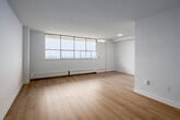 Located on the 19th floor at 2000 Sheppard Avenue West in Toronto, this two-bedroom, one-bathroom unit offers a clean, modern aesthetic throughout. Light-toned hardwood flooring runs seamlessly across the entire space, creating a warm and cohesive feel from room to room.

The spacious living room is a standout feature, with expansive floor-to-ceiling windows that flood the space with natural light and frame sweeping elevated views of the surrounding cityscape and greenery. Baseboard heating runs along the window walls, ensuring comfort year-round.

The kitchen is functional and well-appointed, featuring white cabinetry with a beadboard panel design, a double stainless steel sink, and dark stone-effect countertops — a practical layout for everyday use.

The primary bedroom is generously sized, offering large windows with the same impressive elevated views, a built-in double closet, and ample room to furnish comfortably. The second bedroom also benefits from natural light and includes multiple closet doors for added storage.

The bathroom is finished with white ceramic wall tiles and a full soaking tub with chrome fixtures, maintaining the clean and bright palette seen throughout the unit.

Three hallways connect the rooms efficiently, and the overall layout — as reflected in the floor plan — provides a logical and well-organized flow throughout the unit.