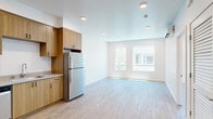 Located at 910 20th Street in Bakersfield, California, this single-story unit offers a thoughtfully laid-out interior finished with contemporary materials throughout. Light-toned luxury vinyl plank flooring runs continuously across all rooms, contributing to a clean, cohesive aesthetic that reflects natural light effectively.

The kitchen is a functional highlight, featuring flat-front wood-toned cabinetry extending to the upper and lower walls, light countertops, a stainless steel refrigerator, dishwasher, range, and microwave. Recessed lighting illuminates the space, which opens toward the living area for an efficient flow between cooking and living zones.

The living and bedroom areas are finished with crisp white walls and recessed lighting, maintaining a bright and neutral environment. Multiple windows admit natural light and provide exterior views, enhancing the openness of each room despite the compact overall footprint.

The bathroom includes a full soaking tub with a shower, toilet, and wood-look flooring that coordinates with the rest of the unit. A dedicated walk-in closet with a full-length hanging rod provides practical storage. Throughout, the design prioritizes clean lines, light finishes, and efficient use of space.