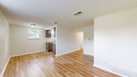Located on Dean Place in Dayton, Ohio, this single-floor unit offers a practical and well-organized layout. Light-toned hardwood flooring runs throughout the main living areas, complementing crisp white walls and trim to create a bright, clean aesthetic.

The open living area is simple and unfussy, with ceiling-mounted ventilation, baseboard heating, and natural light filtering in through a window that offers views of the surrounding neighborhood. The space provides a versatile, move-in-ready canvas.

The galley-style kitchen is efficiently designed, featuring warm-toned wooden cabinetry — both upper and lower — paired with light countertops. White appliances include a gas range and refrigerator, and a double-basin sink sits beneath a window, allowing natural light into the cooking space. Flush ceiling lighting keeps the kitchen well-lit.

The bathroom includes a full-size soaking tub with a bright white surround, built-in recessed shelving niches, and clean, minimal finishes throughout. A connecting hallway ties the rooms together, providing smooth flow and transitions between spaces.

Overall, this unit presents a tidy, functional interior with consistent finishes, making it a straightforward and practical space well-suited to efficient everyday living.