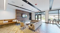 Located on Space Age Road in Madison, Alabama, this contemporary single-floor amenity space is thoughtfully designed to balance social engagement with relaxed comfort. The interior showcases a striking geometric-patterned floor in light wood tones that flows throughout, creating a cohesive visual foundation across all areas of the space.

The lounge area serves as a welcoming focal point, anchored by a full-width reclaimed wood accent wall fitted with a wall-mounted flat-screen television and flanked by navy-toned open shelving. Plush neutral sectional sofas, mid-century-inspired accent chairs, and a round coffee table create an inviting gathering space. A built-in L-shaped leather banquette nook with decorative pillows offers an intimate seating alternative nearby.

The recreation zone features a full-size billiards table positioned beneath a bold sputnik-style chandelier, providing dramatic overhead lighting. A deep teal accent wall adds a pop of color, complemented by framed artwork and a cue rack. High-top bistro tables and bar seating line the floor-to-ceiling window wall, flooding the space with natural light and offering unobstructed views of the landscaped outdoor courtyard, seamlessly connecting the interior to the vibrant surroundings outside.