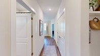 Located at 7035 Primrose Gardens Ln in Charlotte, NC, this single-story, 2-bedroom, 3-bathroom home offers a thoughtfully designed layout with contemporary finishes throughout. The open-concept living and dining area is anchored by warm wood-look flooring, bold accent walls in deep teal, and large windows that invite abundant natural light and outdoor views. A stylish chandelier enhances the dining space, which flows seamlessly into the living area. The kitchen is a standout feature, boasting white shaker cabinetry with matte black hardware, a herringbone tile backsplash, stainless steel appliances, recessed lighting, and a central island with white quartz countertops and pendant lighting — ideal for both cooking and casual dining. Each bedroom offers plush carpeting, ceiling fans, and generous natural light. The primary bedroom connects to a well-appointed en-suite bathroom featuring a dual-sink vanity with white countertops, wood-tone cabinetry, and wood-look flooring. A walk-in closet with built-in shelving provides ample storage. The additional bedroom features a vibrant accent wall and its own bathroom access. Two dedicated closets further enhance the storage options throughout this efficiently designed and visually cohesive home.