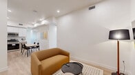 Located at 626 N Wilton Pl in Los Angeles, CA, this modern unit offers five bedrooms and five bathrooms across a thoughtfully designed single-floor layout. The interior is defined by a clean, minimalist aesthetic featuring crisp white walls, light wood-style flooring, and recessed lighting throughout.

The open kitchen is well-appointed with two-tone cabinetry in white and taupe, white quartz countertops, a subway tile backsplash, and a full suite of stainless steel appliances including a gas range, microwave, dishwasher, and refrigerator. A dining table adjacent to the kitchen provides a functional space for shared meals, and colorful wall art adds a touch of personality to the area.

The living room is comfortable and understated, featuring a wall-mounted flat-screen TV, a warm-toned sofa, floor lamps, and a cozy area rug — all set atop the same light hardwood flooring found throughout the unit.

Each bedroom is bright and simply designed, with white walls, light flooring, and windows that bring in natural light. The bedrooms vary slightly in size, with the primary bedroom offering a generous footprint. The five bathrooms maintain a consistent all-white palette, each featuring a tub/shower combination with tiled surround, a floating vanity, and a large mirror.