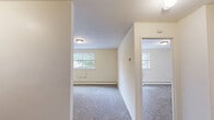 Located at 250 Beverly Blvd in Upper Darby, PA, this one-bedroom, one-bathroom unit offers a practical and efficient single-floor layout. The living room is a comfortable, carpeted space with neutral walls and natural light streaming through windows that offer views of surrounding greenery. Baseboard heating runs along the perimeter, ensuring year-round comfort. The living area connects seamlessly to the kitchen, which features white cabinetry, a refrigerator, and a sink, providing a functional space for everyday meal preparation. The bedroom is a well-sized, carpeted retreat equipped with a wall-unit air conditioner, a baseboard heater, and a window that brings in natural light. It includes a closet and direct access to additional storage, making organization easy. A hallway connects the main living spaces and provides access to the full bathroom, which is finished with classic white tile wainscoting, a vanity with a mirrored medicine cabinet, a toilet, and a tiled floor. Three closets throughout the unit offer generous storage options. The space features consistent light-toned walls and plush carpeting throughout the main rooms, creating a clean and cohesive atmosphere.