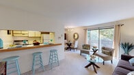 Located at 948 Hartland Rd in Essex, Maryland, this one-bedroom, one-bathroom residence offers a well-organized single-floor layout that maximizes every square foot. The open-concept living area connects seamlessly to the kitchen via a breakfast bar with a wood-toned counter, complemented by two teal bar stools — an inviting spot for casual meals. The kitchen features tile flooring, ample cabinetry, a range, dishwasher, and refrigerator. Large sliding glass doors in the living room flood the space with natural light and provide outdoor views, enhancing the sense of openness. A dedicated dining area accommodates a glass-top table and is accented by a chandelier and an ornate decorative mirror, adding a touch of elegance. The carpeted bedroom is a comfortable retreat with a window overlooking greenery, a built-in closet with bifold doors, and ample room for a full bedroom suite. A hallway with an additional closet provides convenient storage. The full bathroom is clean and functional, featuring hexagonal tile flooring, a combined tub and shower, a vanity with white cabinetry, and a large mirror. Neutral tones and plush carpet throughout create a warm, cohesive ambiance.