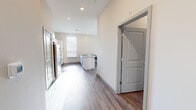 This expansive single-floor unit offers eight bedrooms and five bathrooms, making it an ideal high-occupancy living arrangement. The open-concept kitchen is a standout feature, outfitted with stainless steel appliances including a refrigerator, range, and microwave, complemented by crisp white shaker cabinets with black hardware, a subway tile backsplash, and granite countertops extending across both the perimeter counters and a central island with a built-in sink. Wood-look plank flooring flows consistently throughout the unit, providing a cohesive and durable finish.

The living room receives ample natural light through large windows overlooking outdoor greenery, creating a bright and welcoming communal space. Each bedroom is well-proportioned, with the primary bedroom offering a generous footprint, and all rooms feature windows with horizontal blinds that allow for adjustable light control. The five bathrooms are uniformly finished with white subway tile tub-and-shower surrounds, granite-top vanities with shaker-style cabinetry, and chrome fixtures. A central hallway connects the various rooms efficiently, and recessed lighting throughout ensures consistent illumination across the entire unit. The clean, neutral color palette and modern finishes give the space a contemporary and functional character.