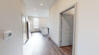 This expansive single-floor unit offers eight bedrooms and five bathrooms, making it an ideal high-occupancy living arrangement. The open-concept kitchen is a standout feature, outfitted with stainless steel appliances including a refrigerator, range, and microwave, complemented by crisp white shaker cabinets with black hardware, a subway tile backsplash, and granite countertops extending across both the perimeter counters and a central island with a built-in sink. Wood-look plank flooring flows consistently throughout the unit, providing a cohesive and durable finish.

The living room receives ample natural light through large windows overlooking outdoor greenery, creating a bright and welcoming communal space. Each bedroom is well-proportioned, with the primary bedroom offering a generous footprint, and all rooms feature windows with horizontal blinds that allow for adjustable light control. The five bathrooms are uniformly finished with white subway tile tub-and-shower surrounds, granite-top vanities with shaker-style cabinetry, and chrome fixtures. A central hallway connects the various rooms efficiently, and recessed lighting throughout ensures consistent illumination across the entire unit. The clean, neutral color palette and modern finishes give the space a contemporary and functional character.