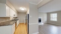 Located at 264 British Woods Dr in Nashville, TN, this 2-bedroom, 3-bathroom residence offers a well-designed single-floor layout that balances comfort and functionality. The open-concept living, dining, and kitchen area serves as the heart of the home, highlighted by light hardwood-style flooring, crown molding, and a classic white-mantled fireplace with a tiled hearth that anchors the living space. Large windows and a glass door flood the area with natural light and provide access to a private balcony. The galley-style kitchen is well-appointed with granite countertops, white cabinetry, stainless steel appliances including a dishwasher and refrigerator, and a deep undermount sink. Both bedrooms feature plush carpeting and windows that bring in natural views of the surrounding greenery, with ample closet storage provided by four closets throughout the unit. The three bathrooms are finished with granite-top vanities, white cabinetry, and light hardwood-style flooring, with at least one bath offering a full soaking tub. A central hallway connects the private spaces seamlessly. The textured ceilings and neutral warm-gray palette throughout lend a cohesive, move-in-ready aesthetic to this Nashville residence.