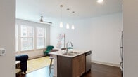 This well-designed single-floor unit combines contemporary finishes with a functional, open layout. The kitchen serves as the heart of the space, showcasing warm wood-tone cabinetry, granite countertops, a stainless steel appliance suite including a refrigerator, range, and built-in microwave, and a large center island with pendant lighting overhead and seating for two. A tile backsplash adds a clean, modern touch throughout the cooking area. Rich, dark hardwood-style flooring flows seamlessly across the entire unit, anchoring each room with warmth and cohesion. The living areas are bright and airy, benefiting from natural light admitted through multiple windows fitted with blinds, and ceiling fans to promote comfortable airflow. A dedicated flex room offers generous space and flexibility for a variety of uses, complete with its own ceiling fan and window. The bedroom hallway features panel-style doors and ample closet access, maintaining a clean, organized aesthetic. The bathroom is finished with granite vanity countertops, wood-tone cabinetry, large-format tile surrounding the tub-shower combination, and hardwood-style flooring, creating a cohesive and polished look throughout the entire unit.