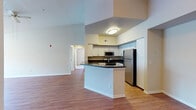 This single-story residence offers a well-designed open-concept layout that maximizes both space and functionality. The living and dining areas are united by warm hardwood-style flooring and impressively tall ceilings that lend an airy, expansive feel throughout the main living spaces. Pendant lighting accents the dining area, while large windows invite natural light and outdoor views into the room.

The kitchen is positioned at the heart of the home, centered around a peninsula with dark countertops that provides both prep space and a casual dining option. White cabinetry lines the walls, complemented by a full suite of stainless steel appliances including a refrigerator, electric range, and built-in microwave. A built-in cabinetry nook with dark countertop adds additional storage near the dining space.

The bedrooms feature plush carpeting, ceiling fans, and generous windows that bring in natural light. Each bedroom is outfitted with a walk-in closet, offering ample storage. The bathrooms are finished with white cabinetry, dark granite-style countertops, and hardwood-style flooring. One bathroom includes a full tub-shower combination, while another features a bright vanity with mirror and track lighting. Together, these spaces create a comfortable and cohesive living environment.