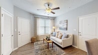 Located at 14500 E Bannister Rd in Kansas City, Missouri, this single-floor residence offers a thoughtfully designed layout with contemporary finishes throughout. The living area is bright and welcoming, featuring durable wood-style flooring, a ceiling fan with light fixture, a textured ceiling, and large windows dressed with striped curtains and horizontal blinds that allow generous natural light to fill the room.

The kitchen is equipped with stainless steel appliances — including a refrigerator, range, and microwave — complemented by white shaker-style cabinetry and granite-style countertops. A peninsula island with seating for two, illuminated by pendant lighting overhead, serves as both a functional workspace and casual dining area.

The bedroom is a restful retreat finished with plush carpet, ample space, and direct access to a walk-in closet outfitted with wire shelving and hanging rods. The bathroom features a white vanity with granite-style countertops, a framed mirror, and wood-style flooring, offering a clean and refined aesthetic.

A dedicated in-unit laundry area houses a full-size washer and dryer with additional wire shelving above for storage. Throughout the space, neutral gray walls and consistent flooring choices create a cohesive, modern ambiance.