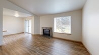 Located in Lakewood, Washington, this two-bedroom, one-bathroom residence offers a practical and comfortable single-floor layout. Wood-look plank flooring runs consistently throughout, lending warmth and visual continuity to every room.

The combined kitchen and living area serves as the heart of the home. The living room is highlighted by a tile-surround fireplace, a large window framing outdoor greenery, and sliding glass doors opening to a private balcony. The kitchen features a peninsula with light stone-tone countertops, warm wood cabinetry extending to the ceiling, and stainless steel appliances including a refrigerator and range.

A central hallway connects the main living areas to the bedrooms and bathroom. The spacious primary bedroom receives natural light through a dedicated window with outdoor views. The second bedroom is well-sized with direct hallway access. Both rooms benefit from multiple closets, with four closets distributed throughout the unit for generous storage.

The full bathroom includes a combined tub and shower, a wood-vanity with a large mirror, and consistent wood-look flooring. A dedicated laundry area adds everyday convenience. Neutral wall tones and clean lines throughout create a bright, understated ambiance well-suited for comfortable living.
