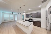 Located at 6131 Louetta Road in Spring, TX, this single-floor, 2-bedroom, 2-bathroom residence offers a thoughtfully designed layout with modern finishes throughout. The kitchen serves as a central highlight, featuring dark espresso shaker cabinets, granite countertops, a large center island with a built-in sink, stainless steel appliances, and stylish pendant lighting — all complemented by light wood-look flooring that extends through the main living areas. Both bedrooms are carpeted and bathed in natural light from double windows dressed with horizontal blinds, and each is equipped with a ceiling fan for year-round comfort. The primary bedroom includes a dedicated closet and an en-suite bathroom with a dual-sink granite vanity, wood cabinetry, and a separate tiled shower. The second bathroom mirrors the refined aesthetic with a granite vanity, a soaking tub with subway tile surround, and direct access to an additional closet. Crisp white walls, clean lines, and consistent finishes throughout the space create a cohesive and contemporary ambiance. Two dedicated closets provide ample storage, rounding out this practical yet polished residence in the Spring, TX area.
