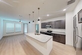 Located at 6131 Louetta Road in Spring, TX, this 2-bedroom, 2-bathroom residence offers a clean, contemporary design with consistent finishes throughout. The open-concept kitchen serves as the heart of the home, anchored by a large center island with a granite countertop, undermount sink, and stylish pendant lighting overhead. Dark espresso cabinetry lines the walls, complemented by stainless steel appliances including a refrigerator, electric range, and microwave. Light-toned luxury vinyl plank flooring flows through the main living and kitchen areas, enhancing the bright, airy atmosphere. Both bedrooms are comfortably sized, featuring plush carpeting, ceiling fans, and windows with blinds that allow natural light to fill each room. Each bedroom is paired with its own closet for dedicated storage. The two bathrooms mirror the kitchen's design language, showcasing dark cabinetry, granite-topped vanities, and light vinyl flooring. The primary bathroom features a dual-sink vanity and a separate tiled shower, while the secondary bathroom includes a tiled soaking tub and shower combo with direct access to a walk-in closet. Ceiling fans are present throughout the unit, ensuring comfort year-round in this well-designed Spring, TX residence.