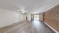 This single-floor residence offers a well-organized layout across two bedrooms and two bathrooms. The living room serves as the central gathering space, featuring durable wood-look laminate flooring, a ceiling fan with light fixture, and a charming brick accent wall that adds texture and character. A sliding glass door allows natural light to fill the room while providing access to an outdoor balcony with exterior views. The front entry area echoes the same warm flooring and open feel.

The kitchen is equipped with warm oak cabinetry, granite-style countertops, a dishwasher, and a gas range, with a window providing natural light. It connects conveniently to the living area via an open passageway.

Both bedrooms are carpeted and finished with neutral tones, offering a quiet, comfortable atmosphere. Each room includes a window for natural light and closet storage, with the primary bedroom featuring a spacious sliding-door closet.

The two bathrooms are clean and functional. One includes a full tub-shower combination with a window above, wood-look tile flooring, and a vanity with warm cabinetry. The second bathroom provides a compact vanity and toilet setup with a mirrored medicine cabinet.