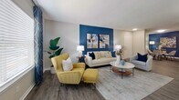 This single-story residence in Alabaster, Alabama offers 1,130 square feet of well-appointed living space across 3 bedrooms, 4 bathrooms, and 2 closets. The open-concept living room features durable wood-look LVP flooring, a bold navy accent wall with coordinating artwork, and a textured ceiling, creating a vibrant yet welcoming atmosphere. The kitchen is outfitted with crisp white shaker cabinetry, granite countertops, stainless steel appliances including a refrigerator, dishwasher, and range, plus a deep undermount sink — all complemented by the same wood-look flooring. The primary bedroom spans 160 square feet and showcases a striking blue accent wall with a ceiling fan, plush carpet, and ample natural light. A secondary bedroom mirrors this calming aesthetic with a soft blue-gray accent wall and carpet flooring. The bathrooms feature dark wood-look LVP flooring, tub-shower combinations with patterned curtains, and neutral gray walls. Two closets with wire shelving provide practical storage. The overall design carries a cohesive, modern color palette of blues, grays, and whites throughout, delivering a polished and comfortable living environment.
