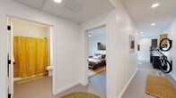 Located at 302 SE D St in Bentonville, Arkansas, this single-story unit offers a thoughtfully designed, modern interior with a clean, minimalist aesthetic throughout. The open-concept kitchen and living area serves as the central hub of the space, where large windows allow natural light to fill the room and provide views of the surrounding streetscape. The kitchen is outfitted with stainless steel appliances, including a full-size refrigerator and range, a combination of gray lower cabinets and warm wood upper cabinetry, white quartz countertops, a subway tile backsplash, and a central island with pendant lighting overhead. A ceiling fan anchors the adjoining living and dining area, creating a cohesive, functional gathering space.

The bedroom features a built-in closet, a ceiling fan, natural light from a window with a blackout shade, and artwork-ready white walls that contribute to a calm, restful atmosphere. A second flexible room accommodates a desk and seating area, functioning well as a home office or additional sleeping space. The bathroom includes a tub-shower combination with white tile surround. A stacked washer and dryer unit is conveniently housed within the unit. Throughout, the flooring is consistent and neutral, reinforcing the space's contemporary, cohesive design.