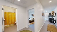 Located at 302 SE D St in Bentonville, Arkansas, this single-story unit offers a thoughtfully designed, modern interior with a clean, minimalist aesthetic throughout. The open-concept kitchen and living area serves as the central hub of the space, where large windows allow natural light to fill the room and provide views of the surrounding streetscape. The kitchen is outfitted with stainless steel appliances, including a full-size refrigerator and range, a combination of gray lower cabinets and warm wood upper cabinetry, white quartz countertops, a subway tile backsplash, and a central island with pendant lighting overhead. A ceiling fan anchors the adjoining living and dining area, creating a cohesive, functional gathering space.

The bedroom features a built-in closet, a ceiling fan, natural light from a window with a blackout shade, and artwork-ready white walls that contribute to a calm, restful atmosphere. A second flexible room accommodates a desk and seating area, functioning well as a home office or additional sleeping space. The bathroom includes a tub-shower combination with white tile surround. A stacked washer and dryer unit is conveniently housed within the unit. Throughout, the flooring is consistent and neutral, reinforcing the space's contemporary, cohesive design.