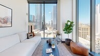 Located in the heart of downtown Austin at 501 Brazos St, this thoughtfully designed one-bedroom, two-bathroom residence combines contemporary aesthetics with functional urban living. The open-concept layout seamlessly connects the kitchen, dining, and living areas, all bathed in abundant natural light from dramatic floor-to-ceiling windows that frame striking views of the Austin skyline.

The kitchen is outfitted with light wood cabinetry, dark stone countertops, black stainless appliances, and a central island with pendant lighting — offering both style and practicality. The living room is bright and airy, anchored by large corner windows that invite sweeping cityscape panoramas.

The bedroom provides a serene retreat, featuring wide-plank wood flooring, textured accent walls, and a full-height window wall that continues the breathtaking downtown views. A dedicated office space adds valuable versatility to the floor plan.

The two bathrooms are distinctly appointed. The primary bath features large-format gray tile, a glass-enclosed walk-in shower, a sleek open vanity with matte black fixtures, and mosaic tile flooring. The second bath echoes the sophisticated palette with floor-to-ceiling stone-look tile and a wall-mounted fixture. Together, the spaces create a cohesive, upscale atmosphere ideal for modern city living.