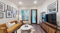 Located at 8733 Rooks Park Cir in Tampa, Florida, this single-story residence showcases a clean, modern aesthetic throughout. The living room is bright and inviting, featuring wood-look plank flooring, recessed lighting, and a bold black-framed exterior door flanked by windows fitted with blinds and sheer curtains that allow natural light to filter in. A gallery wall with framed artwork adds a curated, stylish touch to the space.

The kitchen is well-equipped and thoughtfully designed, featuring two-tone cabinetry with white upper cabinets and dark lower cabinets, granite countertops, a white subway tile backsplash, and a full suite of stainless steel appliances including a refrigerator, range, and microwave. Ample upper cabinet storage and generous counter space make this kitchen both functional and visually appealing.

Both bathrooms are finished with granite countertops, undermount sinks, dark-framed mirrors, and dark cabinetry, lending a cohesive and upscale feel. One bathroom features a double-sink vanity. Wood-look flooring continues throughout these spaces.

The bedrooms are spacious and serene, each offering room for generous furniture arrangements. Neutral wall tones and soft lighting create a calm, restful atmosphere. The overall design blends contemporary style with practical comfort throughout this Tampa residence.
