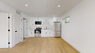 Located at 24332 1/2–24334 1/2 Chestnut St, this thoughtfully designed single-floor unit makes efficient use of its compact footprint. The open-plan layout seamlessly integrates the living room, dining area, and kitchen into one cohesive space, creating an airy and functional environment. The kitchen is outfitted with crisp white shaker cabinets featuring black hardware, light stone countertops, a white tile backsplash, and a full suite of stainless steel appliances including a French door refrigerator, electric range with over-the-range microwave, and a black matte sink — all set above warm-toned light wood flooring that runs throughout the unit. Recessed lighting illuminates the main living area, while horizontal windows invite natural light. The bedroom offers a comfortable, well-proportioned layout with two windows overlooking the outdoors, a double sliding-door closet, a wall-mounted mini-split HVAC unit, and direct sightlines to the kitchen. The bathroom is finished with white square wall tile, a tub-shower combo enclosed by a sleek black-framed glass door, grey stone floor tile, and a white vanity. Additional features include a dedicated laundry area, two closets, and a private patio.