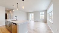 Located at 1211 Carrington Blvd in Mount Pleasant, WI, this 800-square-foot single-floor unit offers a modern, move-in-ready layout with clean design and quality finishes throughout. The open-concept kitchen and living room serve as the heart of the home, featuring light hardwood-style flooring, crisp white shaker cabinetry with black hardware, quartz countertops, a large center island with pendant lighting, and stainless steel appliances including a range, over-the-range microwave, and French door refrigerator. The living area is bright and spacious, with sliding glass door access to the outdoors and additional windows that invite natural light. The 170-square-foot bedroom offers plush carpeting, a generous window with outdoor views, and access to a walk-in closet with wire shelving for organized storage. The full bathroom is well-appointed with a gray vanity, quartz countertop, undermount sink, black matte fixtures, a large mirror, and a soaking tub/shower combination with light hardwood-style tile flooring. Two utility rooms provide additional functional space. Neutral tones and consistent finishes create a cohesive, contemporary ambiance throughout this well-designed unit.