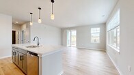 Located at 1211 Carrington Blvd in Mount Pleasant, WI, this 800-square-foot single-floor unit offers a modern, move-in-ready layout with clean design and quality finishes throughout. The open-concept kitchen and living room serve as the heart of the home, featuring light hardwood-style flooring, crisp white shaker cabinetry with black hardware, quartz countertops, a large center island with pendant lighting, and stainless steel appliances including a range, over-the-range microwave, and French door refrigerator. The living area is bright and spacious, with sliding glass door access to the outdoors and additional windows that invite natural light. The 170-square-foot bedroom offers plush carpeting, a generous window with outdoor views, and access to a walk-in closet with wire shelving for organized storage. The full bathroom is well-appointed with a gray vanity, quartz countertop, undermount sink, black matte fixtures, a large mirror, and a soaking tub/shower combination with light hardwood-style tile flooring. Two utility rooms provide additional functional space. Neutral tones and consistent finishes create a cohesive, contemporary ambiance throughout this well-designed unit.