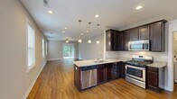 Located at 2775 Stowmarket Ave in Rockford, IL, this single-story home offers a well-designed layout across two bedrooms, two bathrooms, a combined kitchen and living room, a garage, a utility room, and two closets. The living room is bright and spacious, featuring warm hardwood flooring, a ceiling fan, recessed lighting, and a sliding glass door that opens to a wooden deck overlooking a lush, tree-lined backyard — ideal for outdoor relaxation. The kitchen is equipped with rich dark cabinetry, granite countertops, hardwood floors, and stainless steel appliances, creating a functional and stylish cooking space. The primary bedroom is generously sized with plush carpeting, a ceiling fan, and direct access to an en-suite bathroom. The second bedroom also features carpet and a ceiling fan, with ample natural light from a window. Both bathrooms are finished with dark wood vanities and granite countertops; the full bath includes a tub-shower combination and hardwood flooring. Closets are outfitted with wire shelving systems for organized storage. The attached garage is spacious with a concrete floor and automatic opener. The exterior showcases vinyl siding, a back deck, and a sloped green yard bordered by mature trees, offering a peaceful natural setting.
